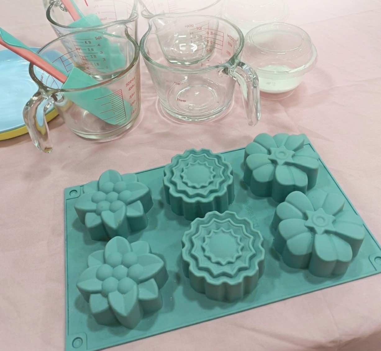 Moldes de silicona con forma de flor y jarras medidoras en la mesa del taller